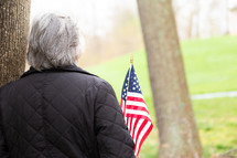 Woman holding american flag near tree