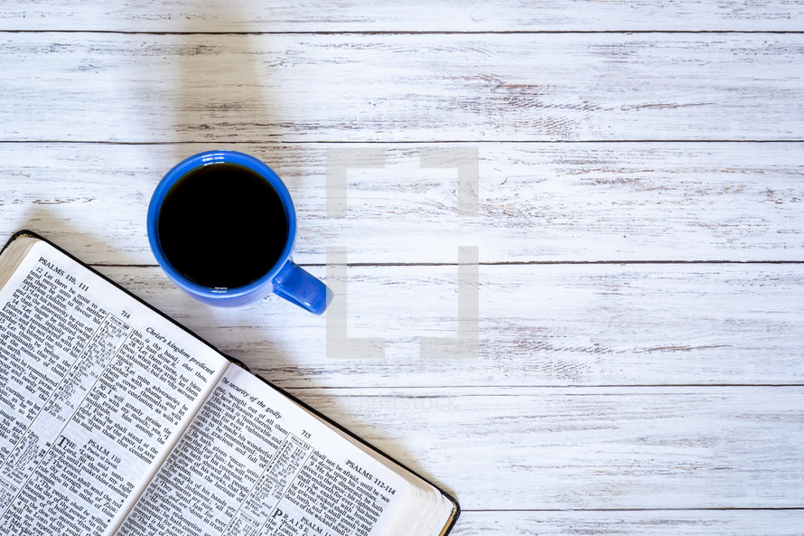 open Bible and coffee mug on a white wood background 
