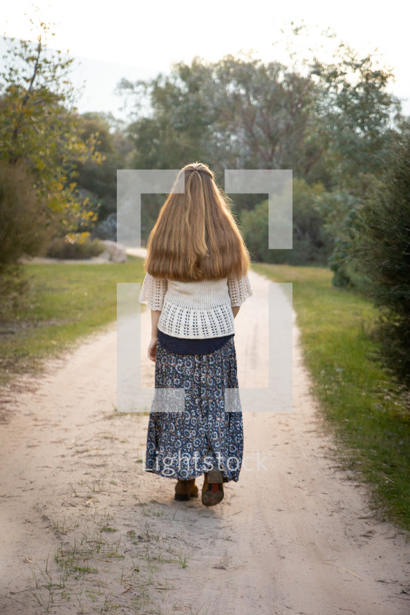 a girl walking on a dirt road 