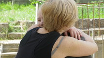 Middle aged woman hugs an elderly woman.