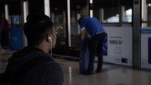 Man with headphones sits at Dubai metro train station waiting for a ride.
