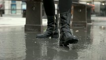 woman in boots splashing in a puddle 