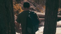 A couple hikes in a forest toward a river