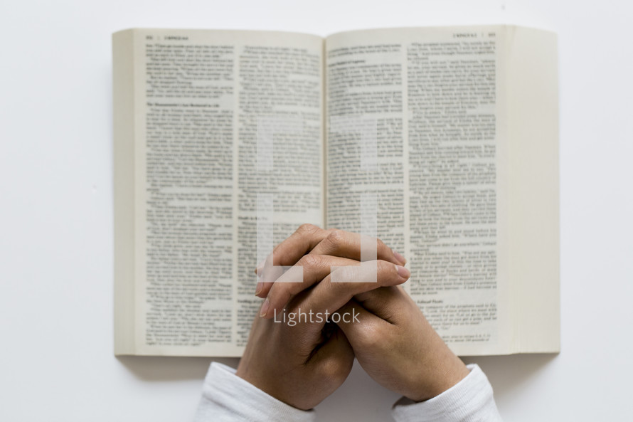 man praying over the pages of a Bible 