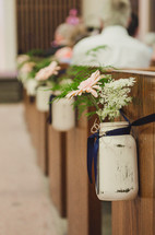 flowers in mason jars at the end of pews 