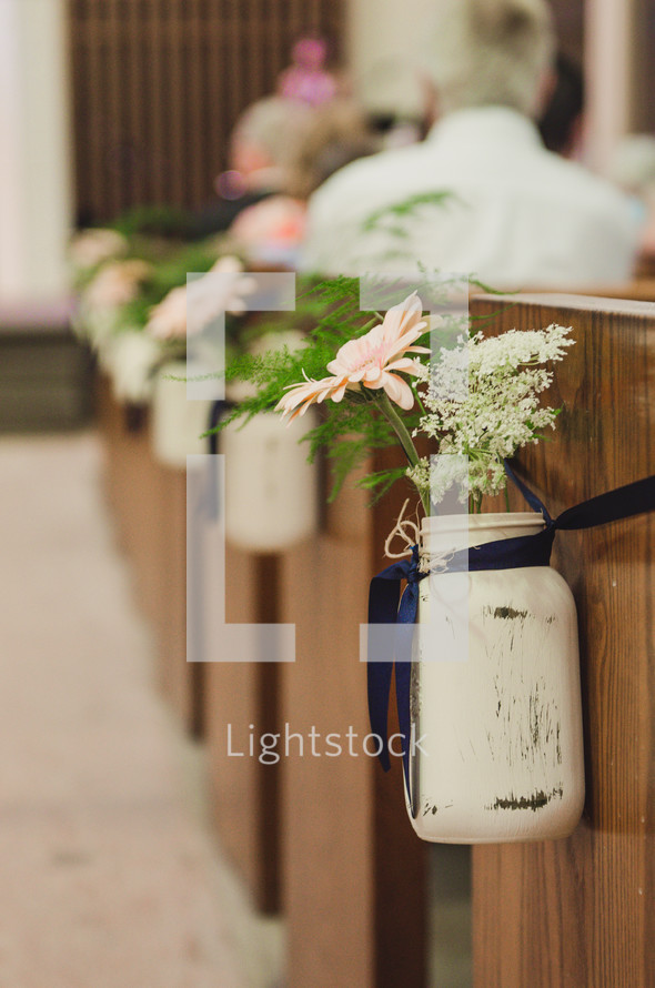 flowers in mason jars at the end of pews 