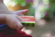 toddler holding a slice of watermelon 