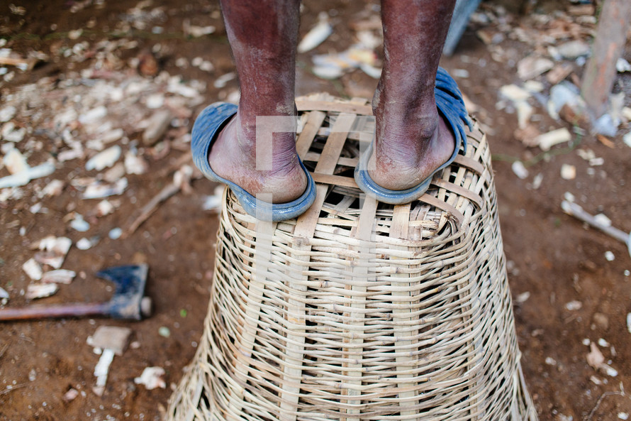 a man in sandals standing on a basket in Kalikhola village 