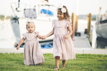 sisters in dresses walking holding hands 
