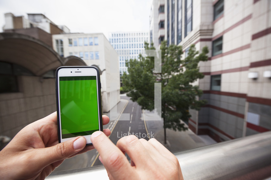 Personal perspective of a man using a smartphone with a green screen - for editorial use only