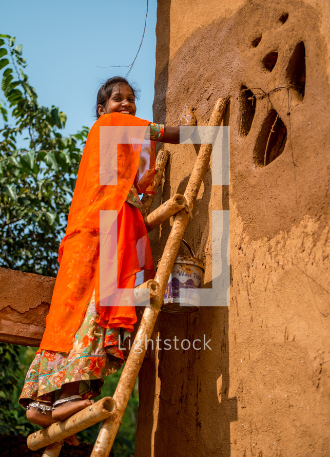 a woman painting a house in India 