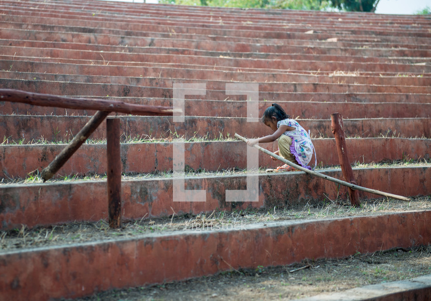 girl child playing with a stick in India 