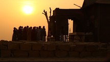 people walking around a desert village at sunset 