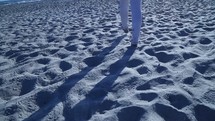 woman's feet walking in the sand on a beach 