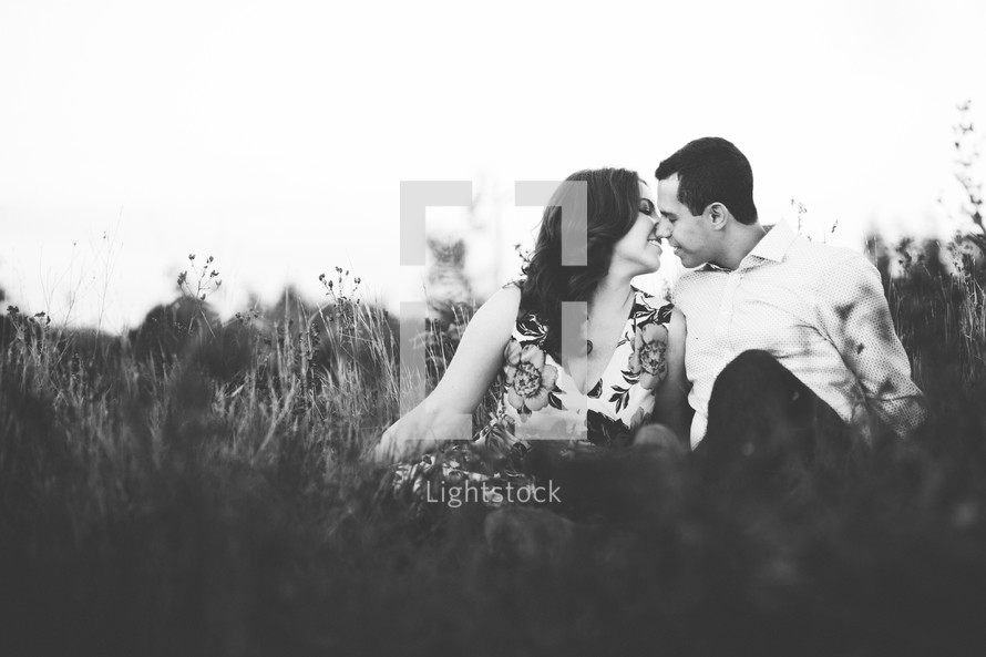 a couple kissing sitting in the grass