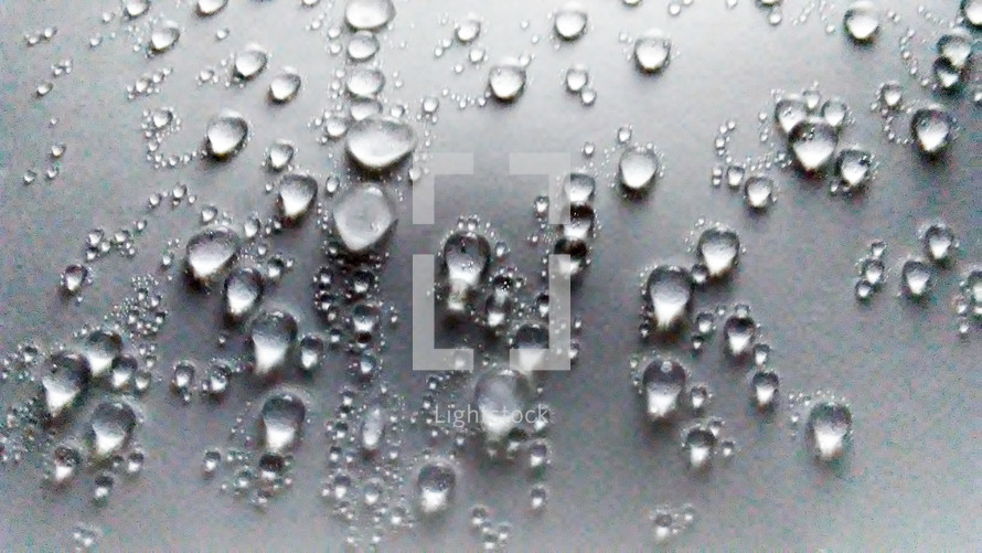 Water droplets appearing on a flat surface after cold and warm air mix and condensation appears on windows and surfaces from cold temperatures warming up due to climate change, weather, storms and ice defrosting. 