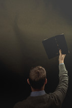 a preacher holding up a Bible during his sermon 