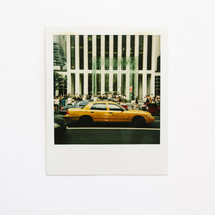 polaroid photograph of a taxi cab in a city 