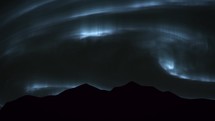 Aurora Borealis over silhouette mountains