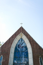 A framed roof church and stained glass window on church exterior 