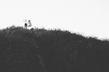 a couple on a hilltop jumping up 