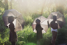 people holding umbrellas in a forest 