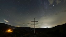 Christian cross in beautiful mountain nature, night sky full of stars with milky way