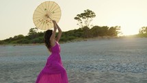 Silhouette of Girl Pink dress and yellow umbrella Dance On Beach