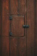 Wooden confessional door with closed priests's window.