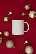 gold Christmas ornaments on a red background and mug