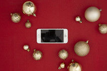 gold Christmas ornaments on a red background and cellphone