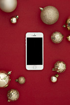 gold Christmas ornaments on a red background and cellphone 