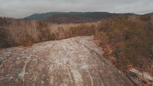 drone shot of a mountaintop and forest in winter 