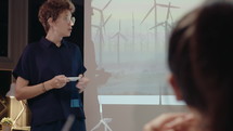 Young Woman Giving Presentation about Renewable Energy on Meeting
