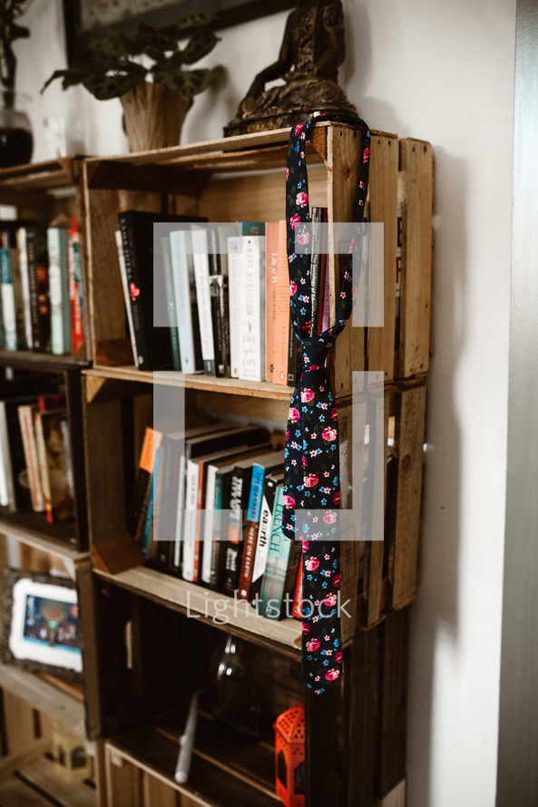 floral tie hanging on a book shelf 