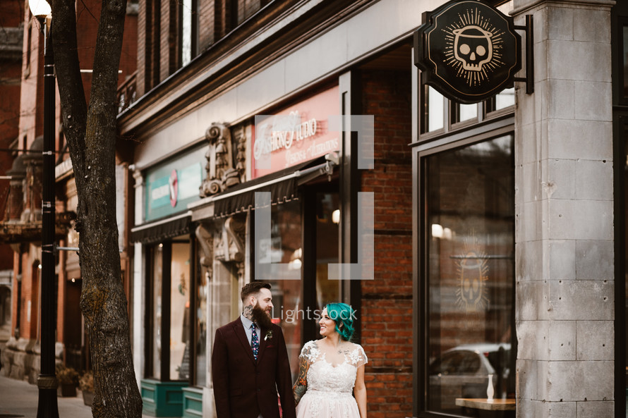 bride and groom standing on a downtown sidewalk 