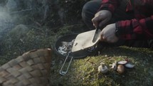 a man cooking outdoors by a fire 