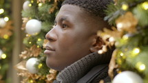 a young man with a blank stare surrounded by Christmas decorations 