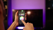 Hand of a man change color light of the house with smart phone, home automation concept