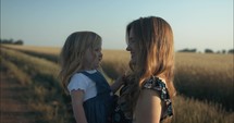 Happy mother and daughter laughing outside on farm in sunset