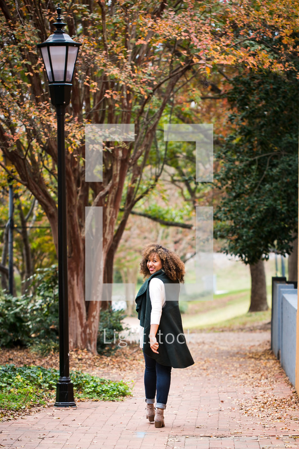 young woman walking on a sidewalk in fall 