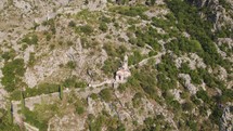 Aerial: Church of Our Lady of Remedy in Kotor, Montenegro's rugged terrain