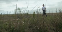 Young man walking on unpaved, dirt road on summer day explore, hiking, worshipping and praying. Lifestyle, worship and prayer concept.