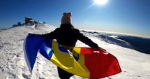 Girl running with the Romanian Flag on top of The Bucegi Mountains in Romania.