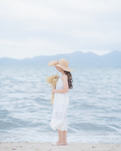 a woman in a white dress walking on a beach 