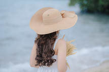 a woman in a hat holding wheat 