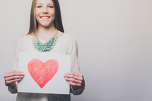 teen girl holding a red heart drawing 