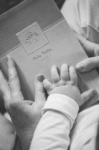 mother and infants hands on a Bible