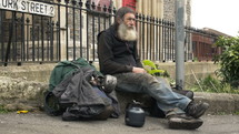 Gray bearded man sitting on the street.