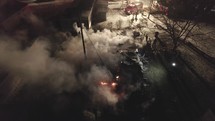 Drone View Of A House On Fire At Night. Firefighter On-Site To Extinguish.